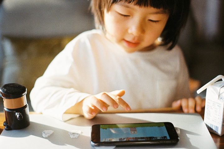 a kid is playing mobile game
